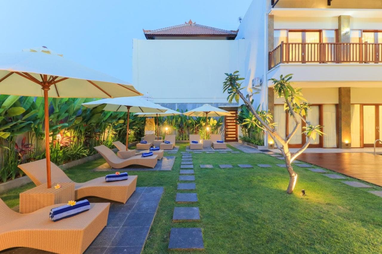 a hotel patio with lounge chairs and umbrellas at Linda Villa 2 in Sanur