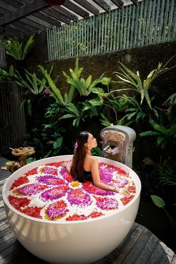 a woman sitting in a bath tub covered in flowers at Kuwarasan A Pramana Experience in Ubud