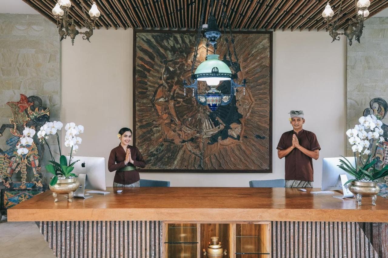 two people standing in front of a table with a painting at Kuwarasan A Pramana Experience in Ubud