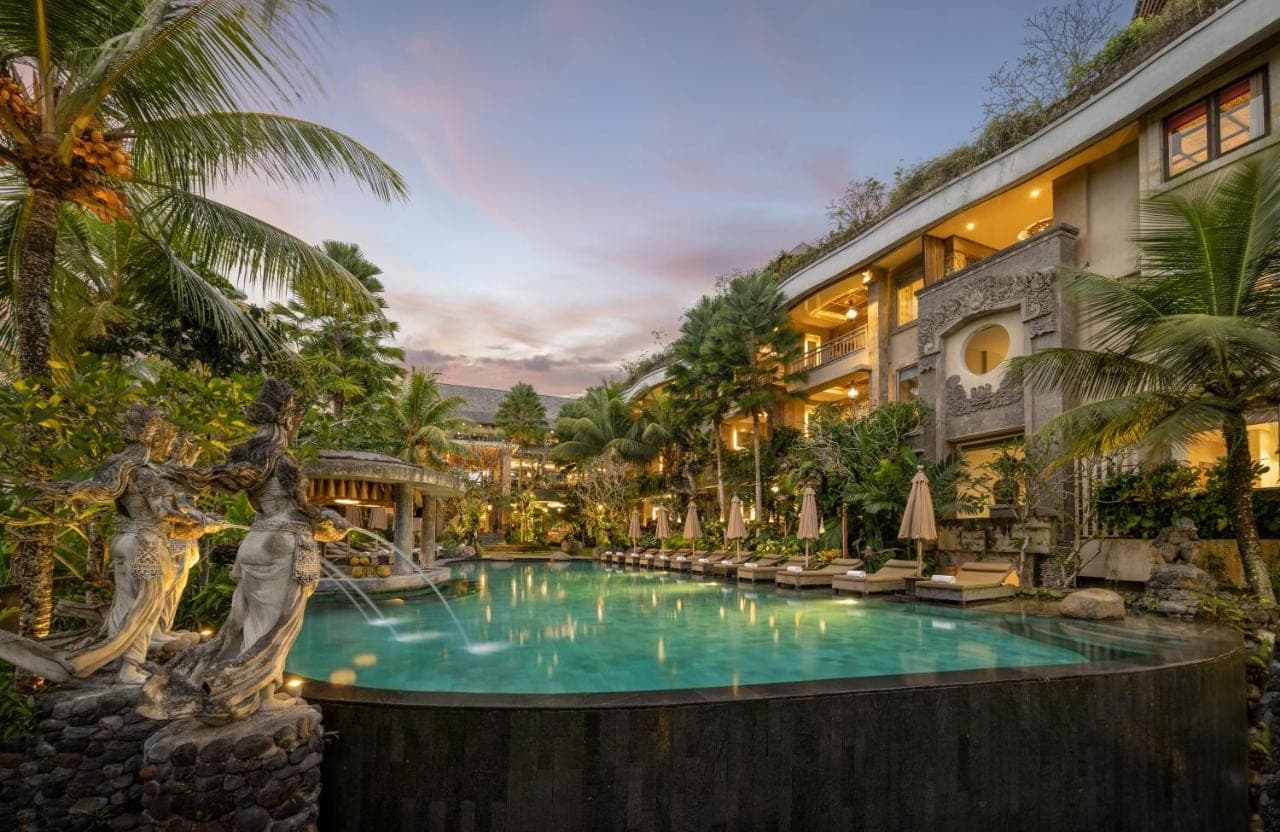 a pool at a resort with palm trees at Kuwarasan A Pramana Experience in Ubud