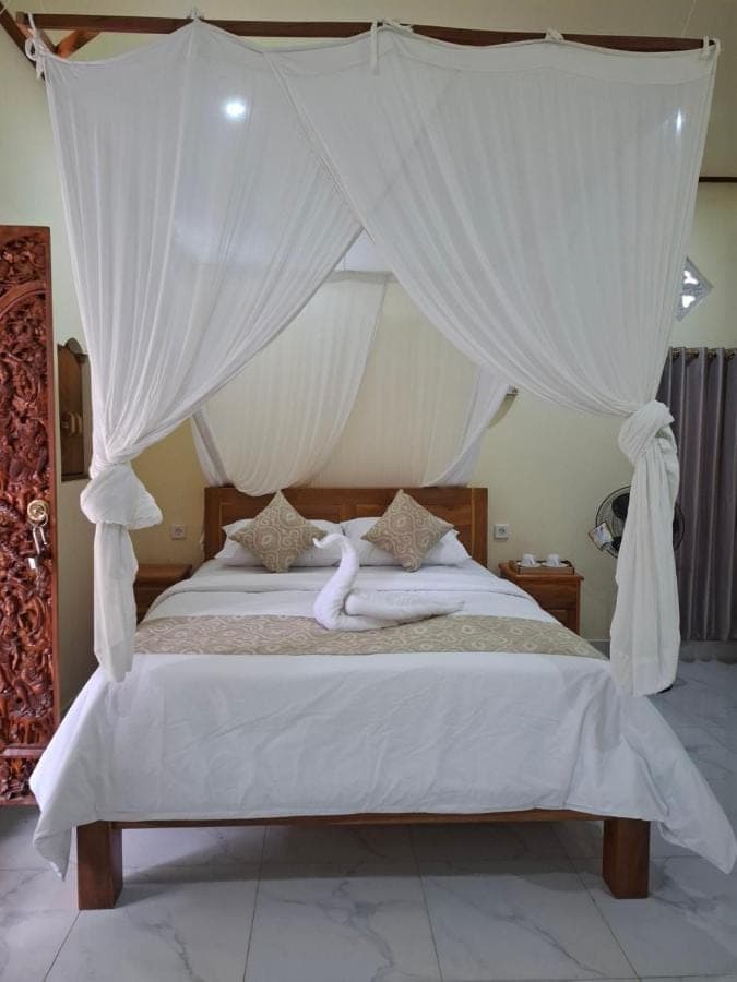 a bedroom with a canopy bed with white curtains at Kelle Homestay in Sidemen