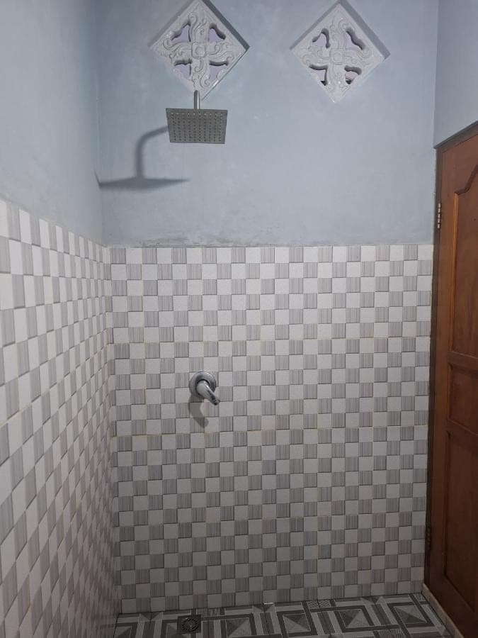a bathroom with a tiled shower with a faucet at Kelle Homestay in Sidemen