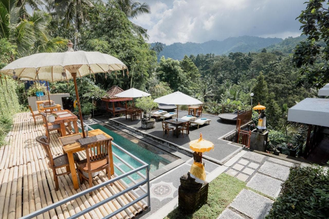 an outdoor patio with tables and chairs and an umbrella at Astana Swaha Villa in Sidemen