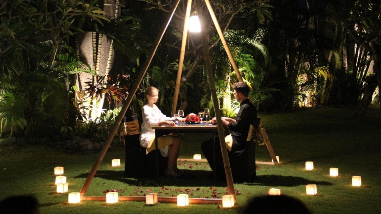 a man and woman sitting at a table with candles at The Wolas Villas in Seminyak