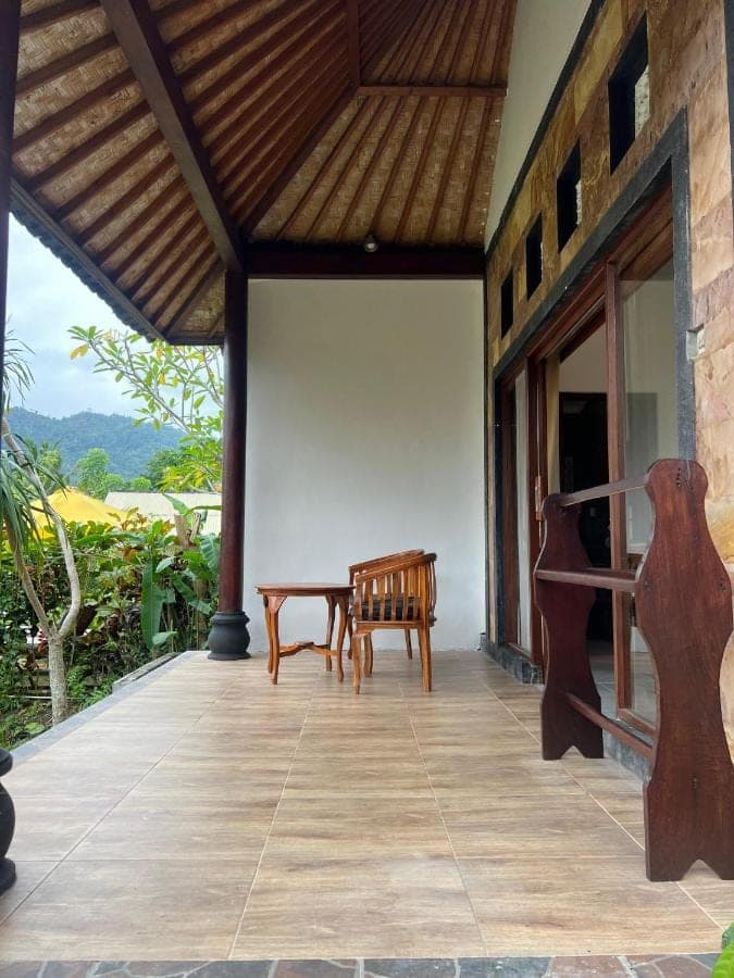 a porch of a house with a bench and a table at Giri Carik in Sidemen