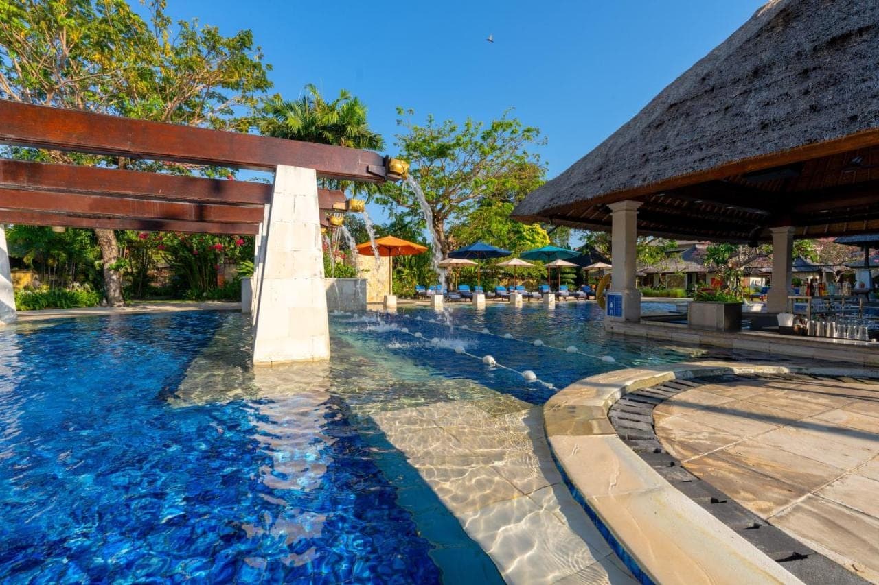 a swimming pool at a resort with a bench at Rama Beach Resort and Villas in Kuta