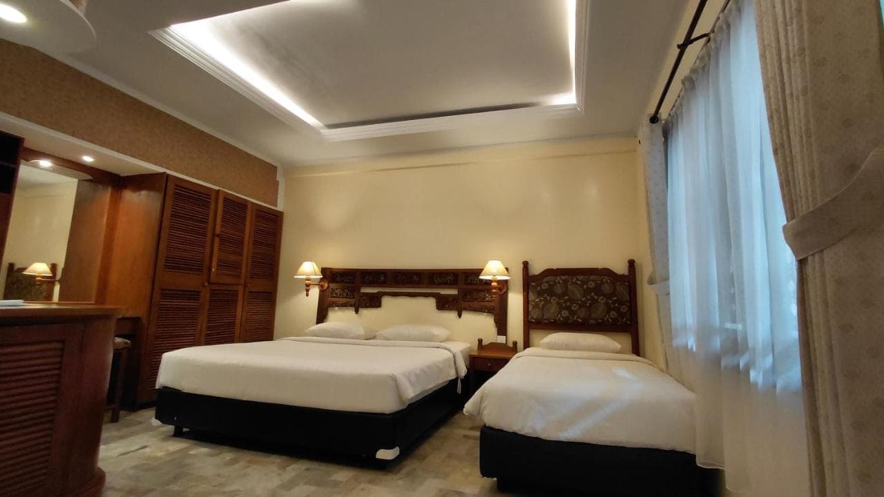 a hotel room with two beds and a window at Bali Bungalo Hotel in Kuta