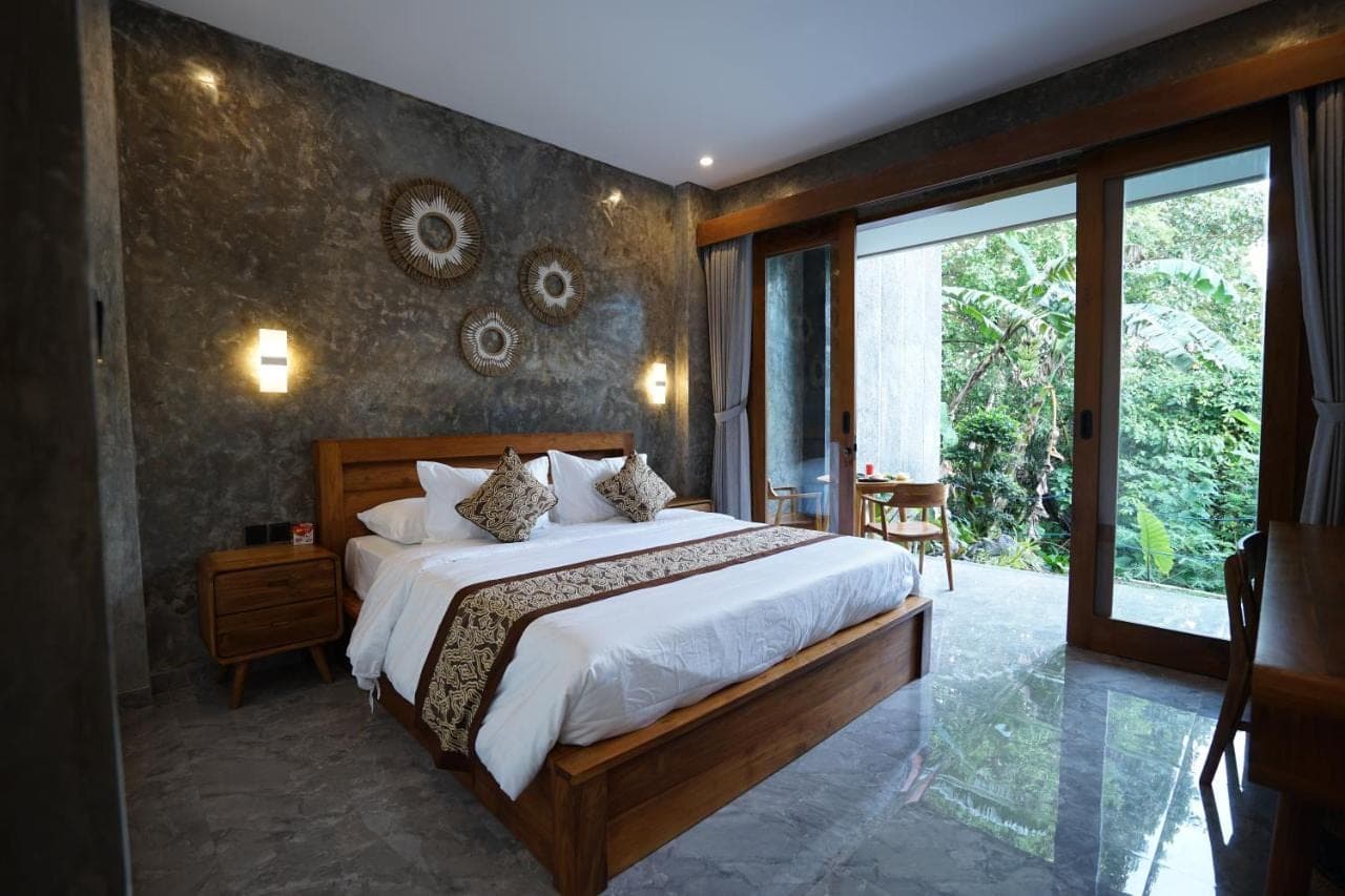 a bedroom with a large bed and a large window at Sandat Garden House in Ubud