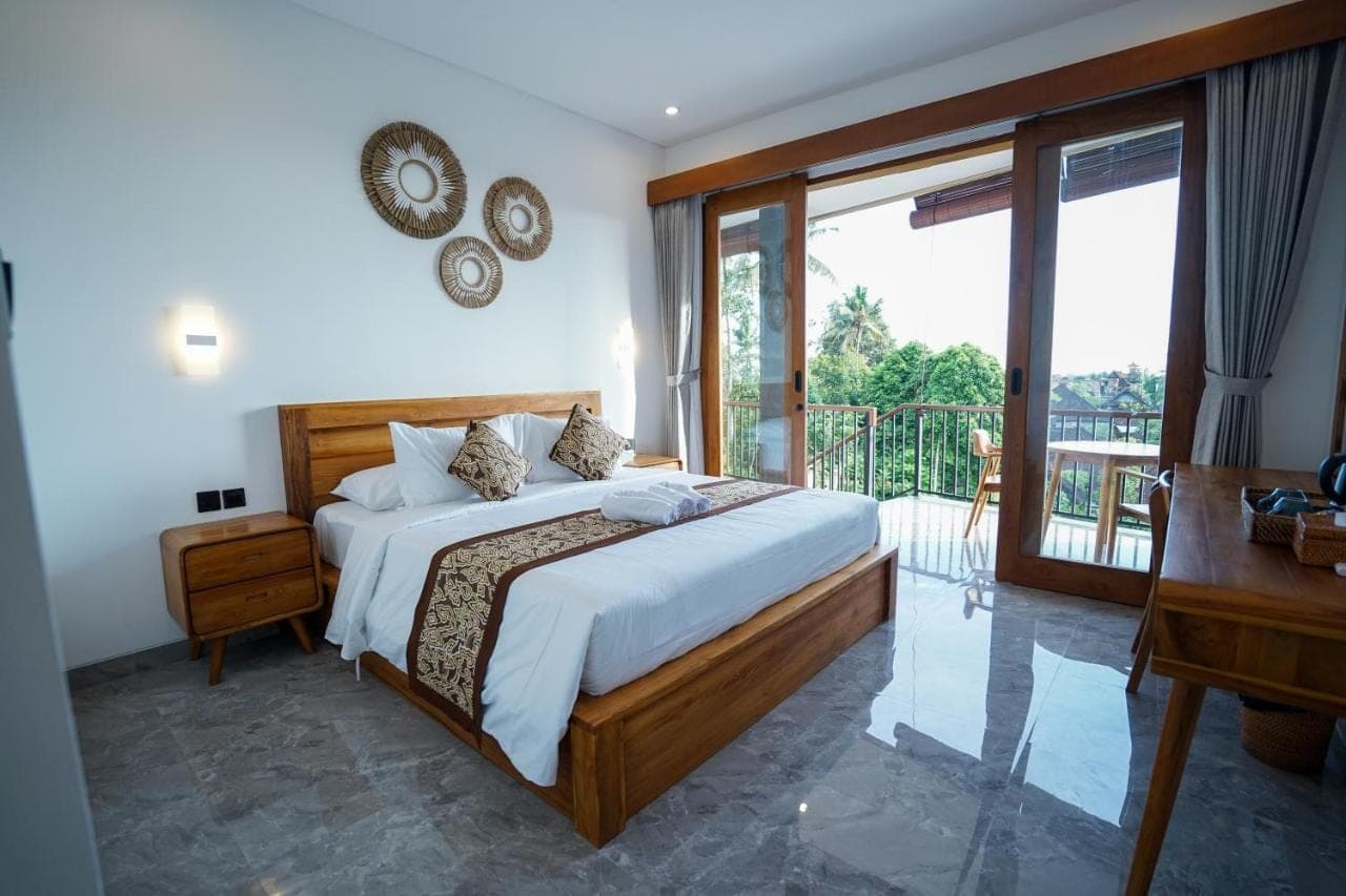 a bedroom with a large bed and a balcony at Sandat Garden House in Ubud