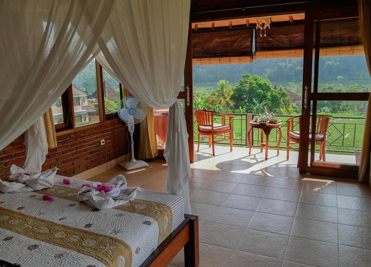 a bedroom with a bed and a balcony with a view at Embang Homestay in Sidemen