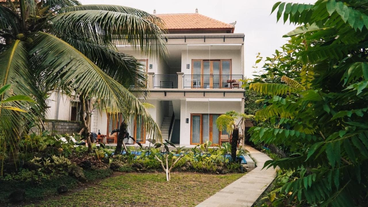 a white house with palm trees in front of it at Myraga House Ubud in Ubud