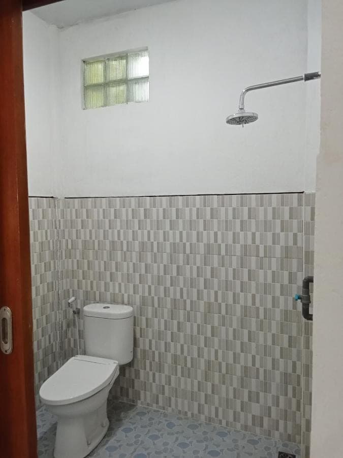 a bathroom with a toilet in a tiled room at KOMANG homestay in Amed