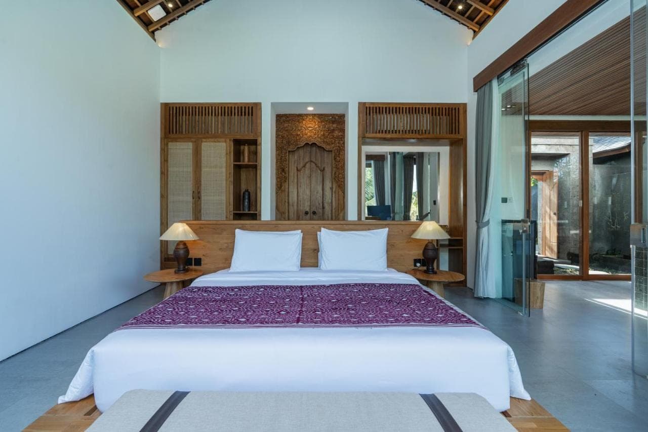 a bedroom with a large bed and two tables at Queen at Gunung Sari in Ubud