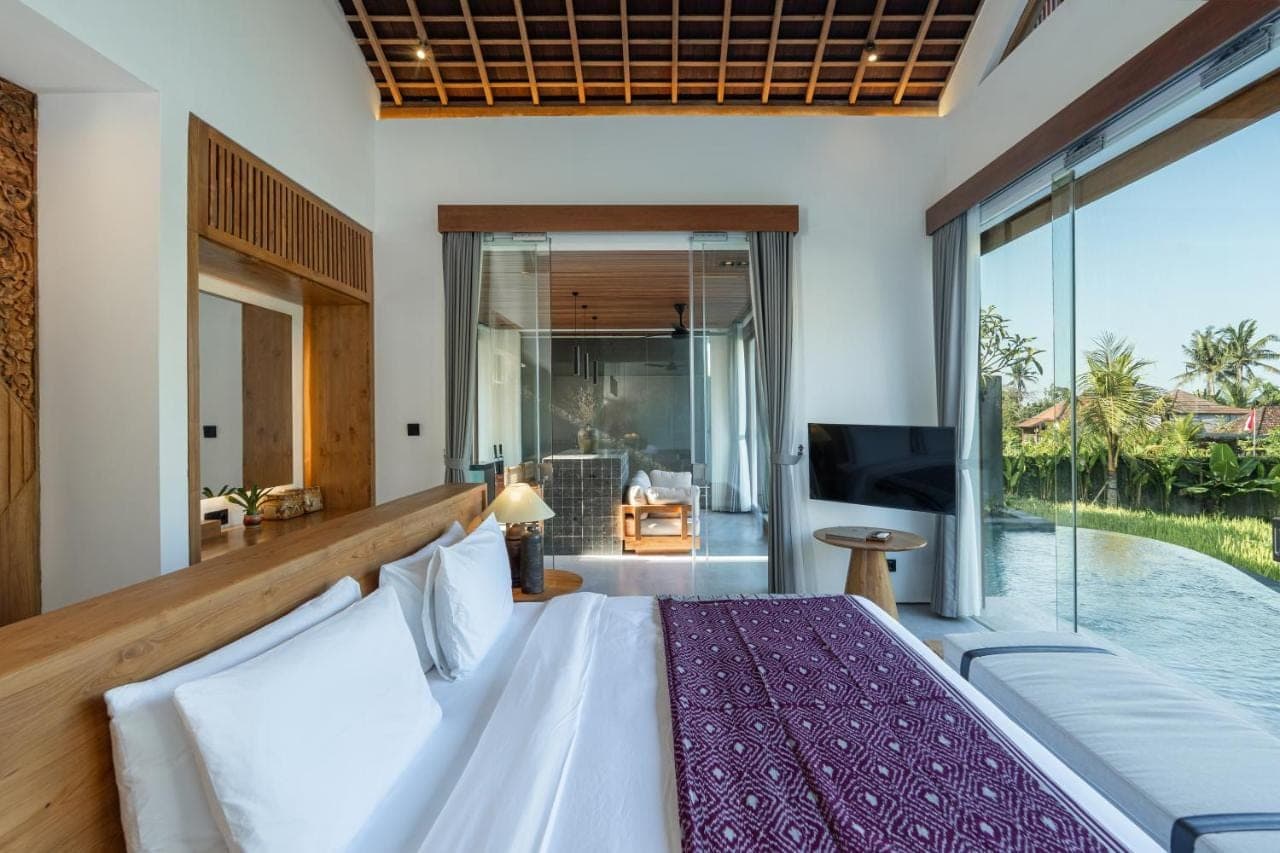 a bedroom with a bed and a view of a pool at Queen at Gunung Sari in Ubud