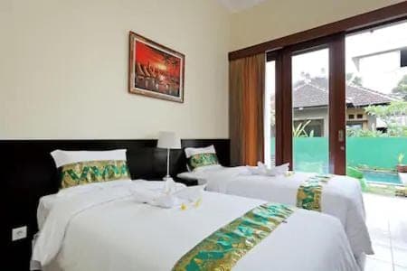 a bedroom with two beds and a large window at Kubu Green in Nusa Dua