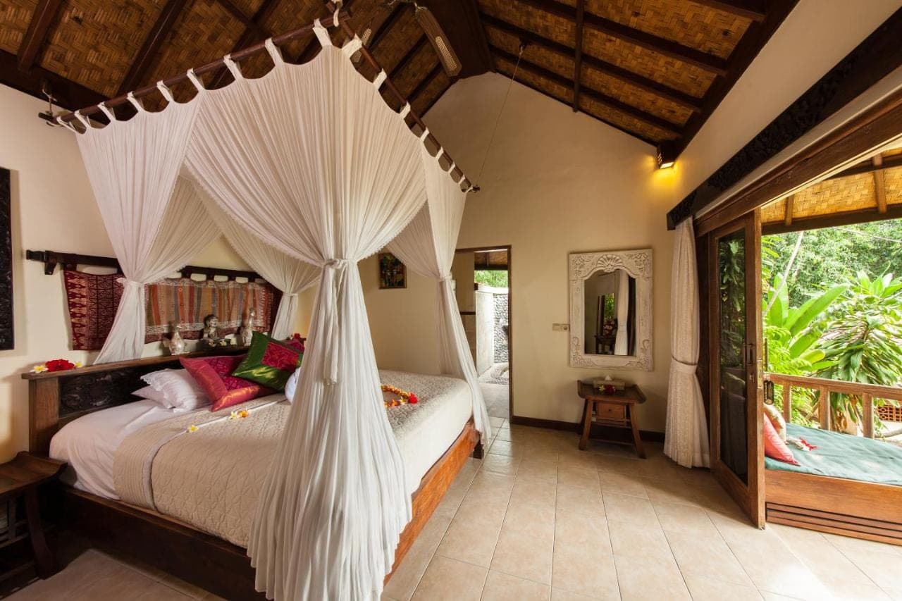 a bedroom with a bed with a net canopy at Blue Moon Villas Resort in Amed