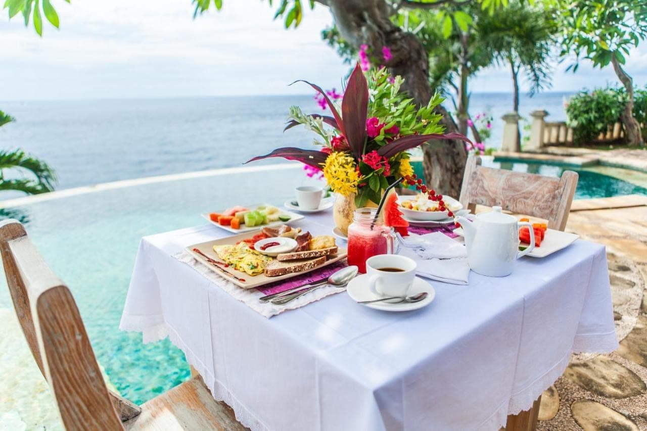 a white table with food on it next to the water at Blue Moon Villas Resort in Amed