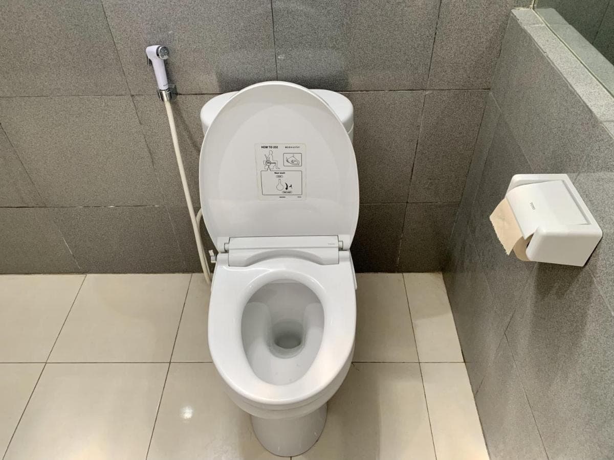 a bathroom with a toilet with a sign on the lid at Davit Guesthouse Nusa Dua in Nusa Dua