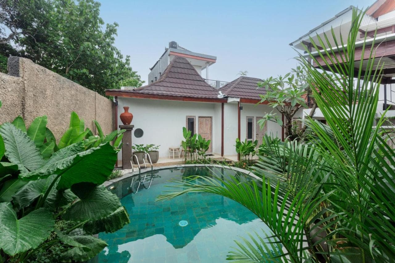 a swimming pool in front of a house with plants at Iconic Lodge Uluwatu in Uluwatu