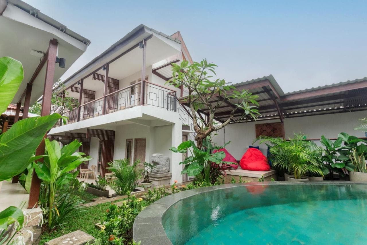 a villa with a swimming pool in front of a house at Iconic Lodge Uluwatu in Uluwatu