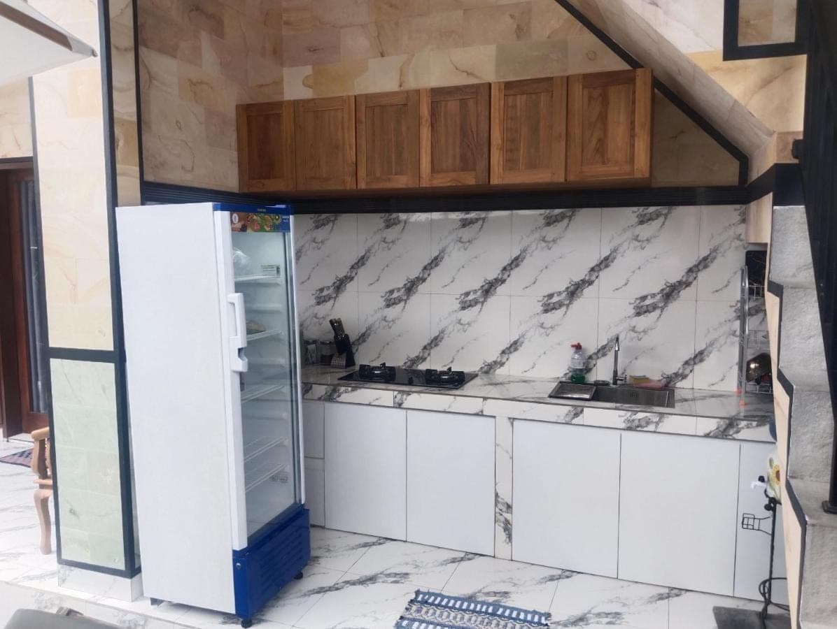 a kitchen with white cabinets and a refrigerator at Leo Home Stay in Canggu