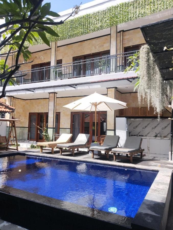 a swimming pool in front of a building at Leo Home Stay in Canggu