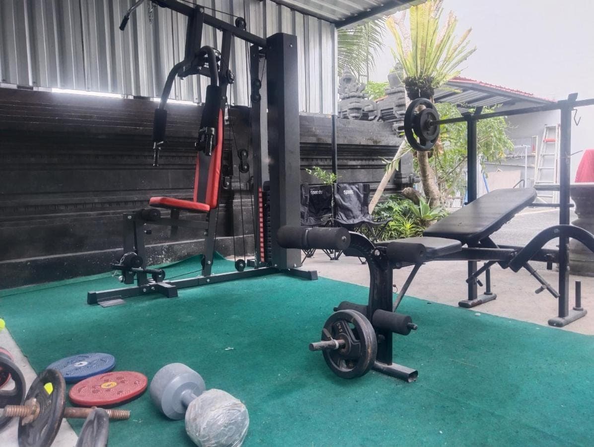 a gym with weights on a green carpet at Leo Home Stay in Canggu