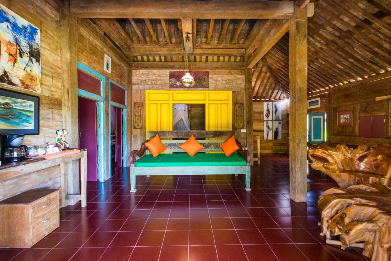 a bedroom with a green bed with orange pillows at Villa Melasti Amed in Amed