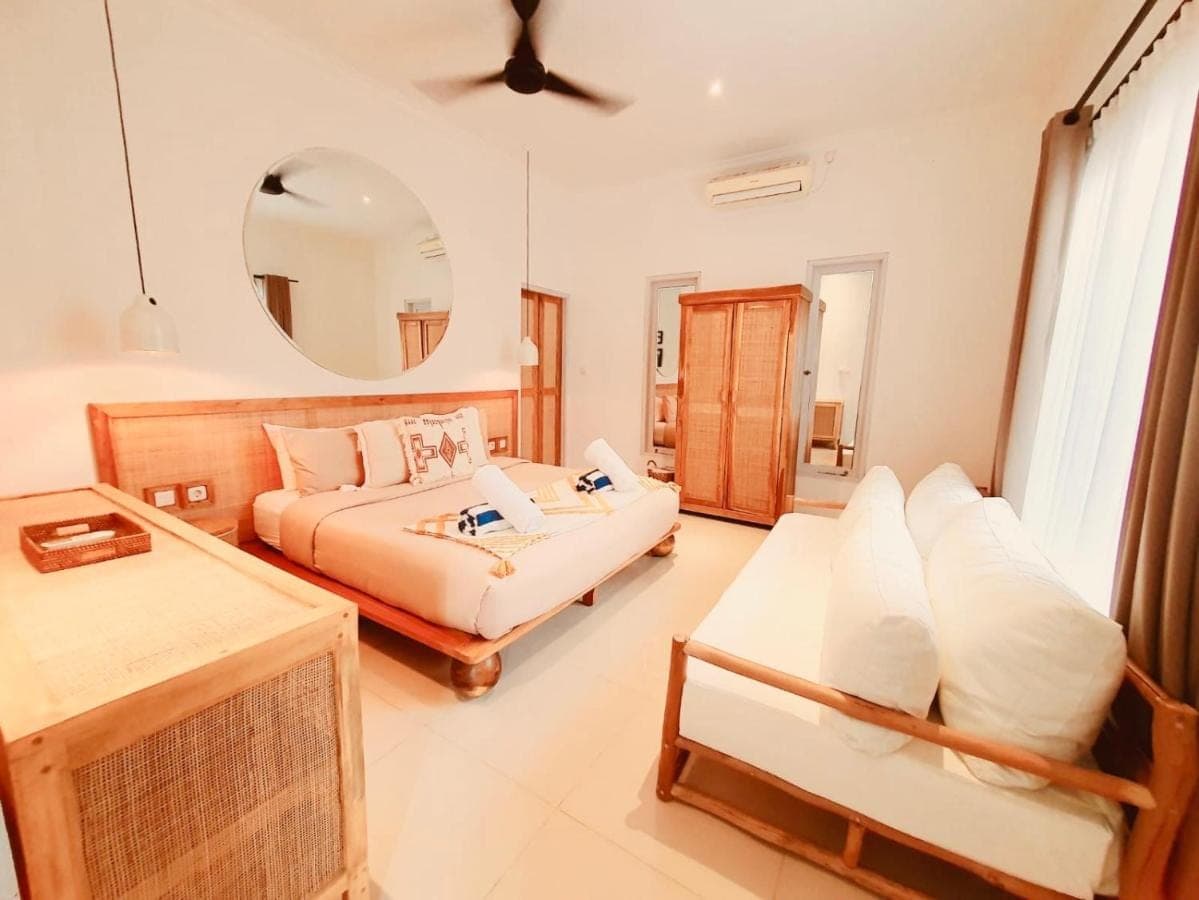 a bedroom with a bed and a couch and a mirror at Love Song Villa Canggu in Canggu