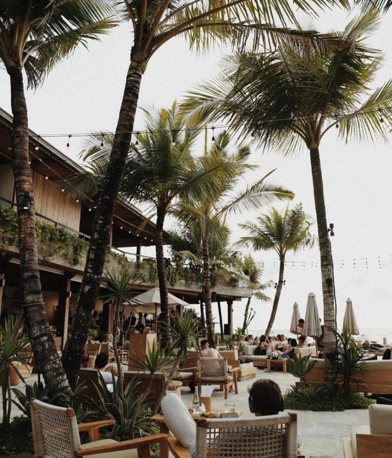 a resort with palm trees and people sitting in chairs at Love Song Villa Canggu in Canggu