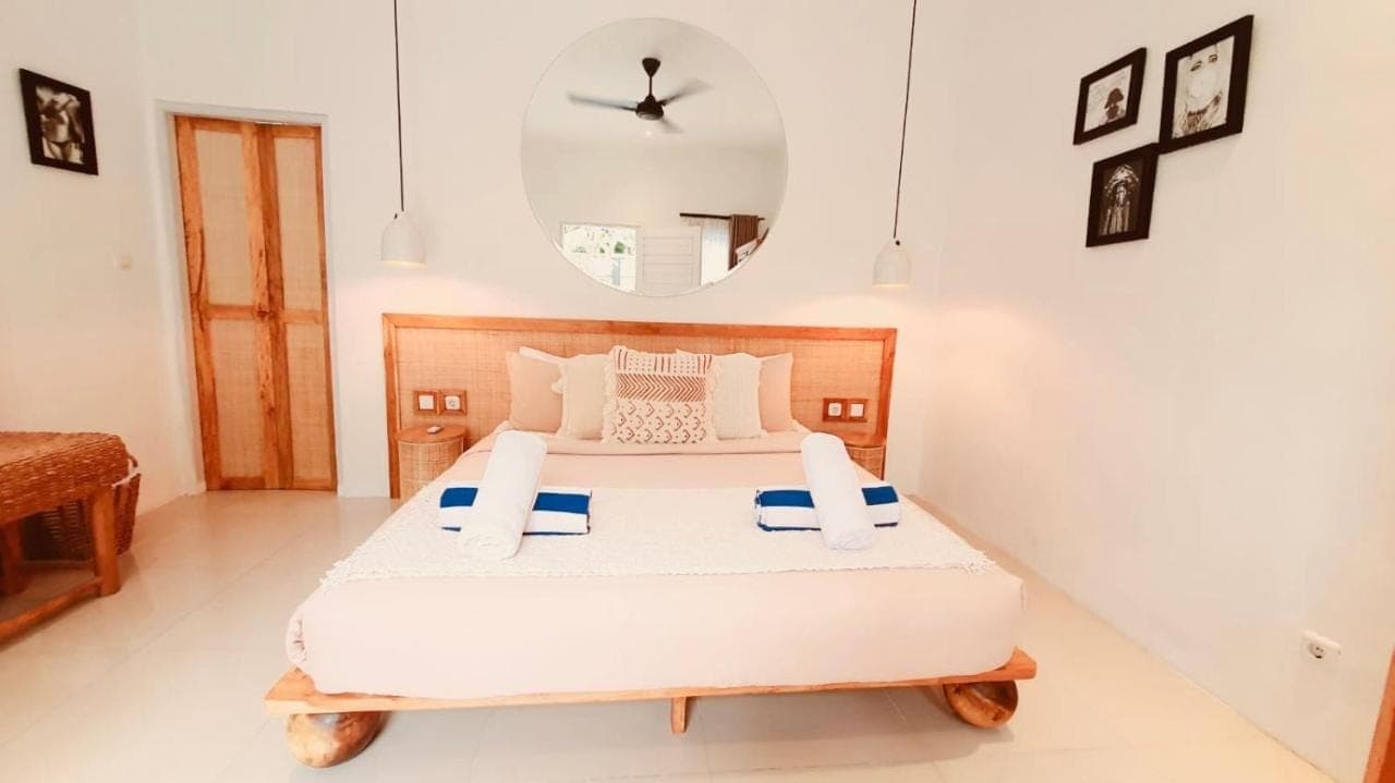 a bedroom with a large white bed with a mirror at Love Song Villa Canggu in Canggu