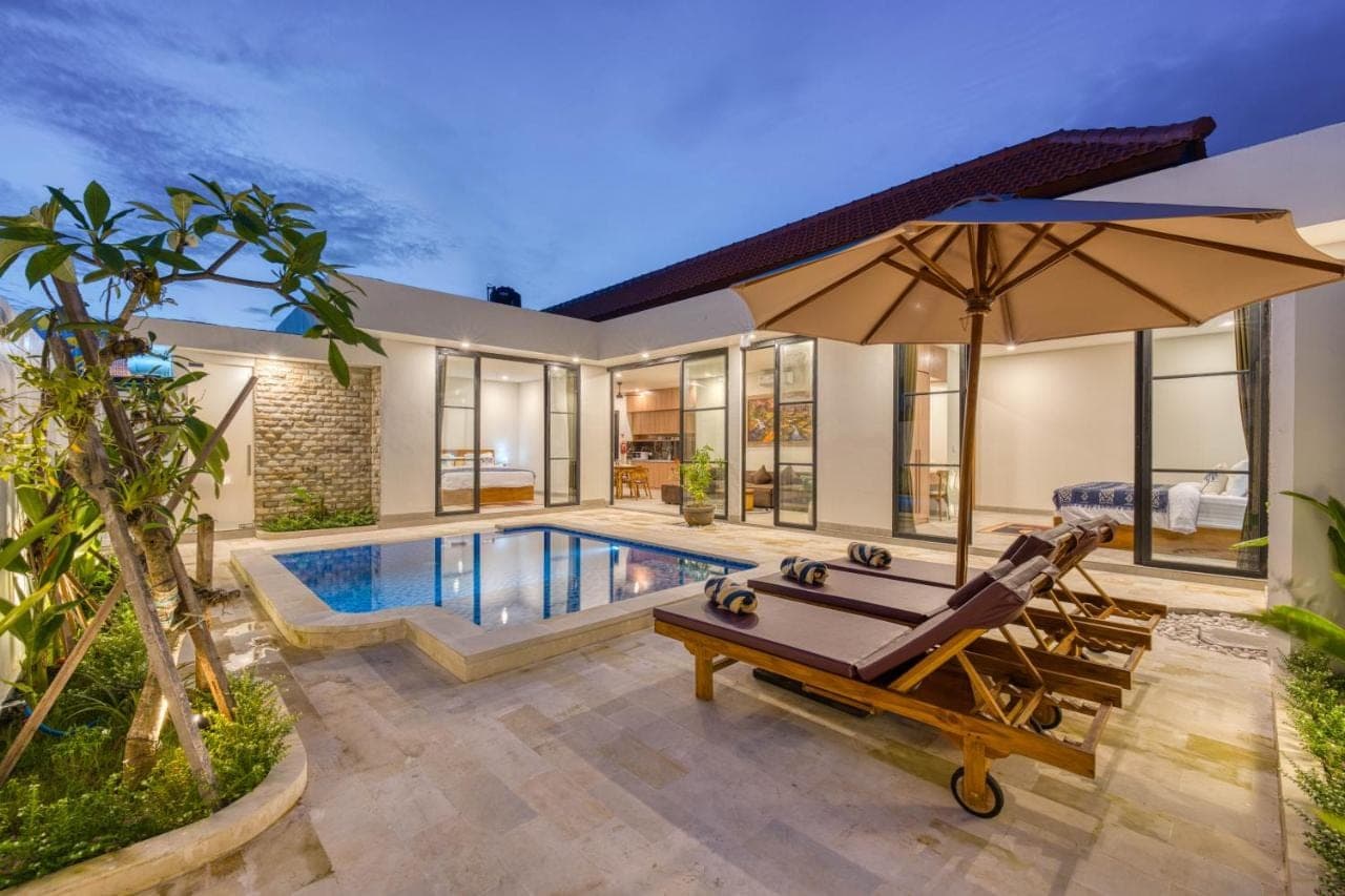 a house with a swimming pool and an umbrella at Narayuka private villa Seminyak in Seminyak