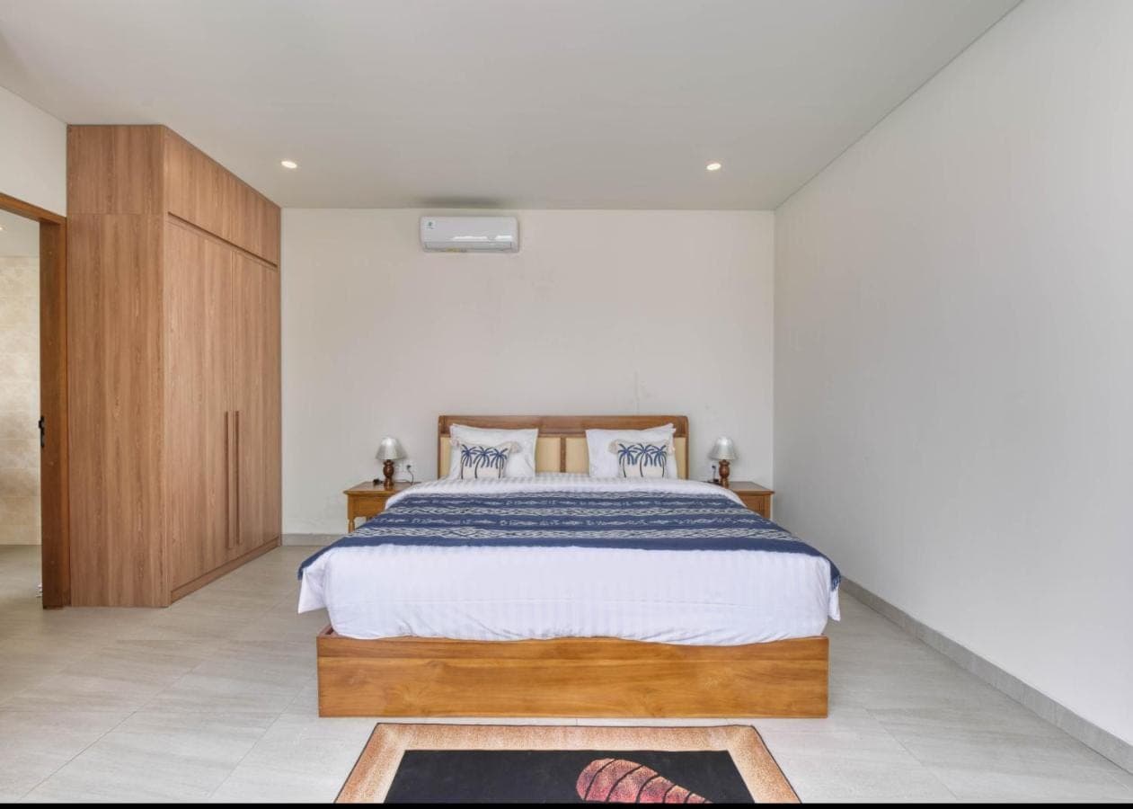 a bedroom with a large bed with a wooden headboard at Narayuka private villa Seminyak in Seminyak