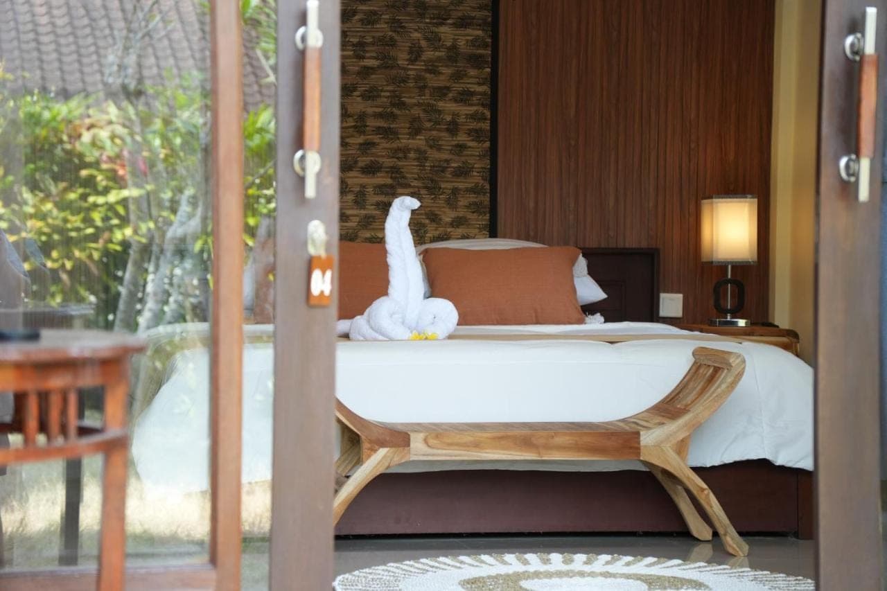 a bedroom with a bed with a swan on it at Alit Bungalow Ubud in Ubud