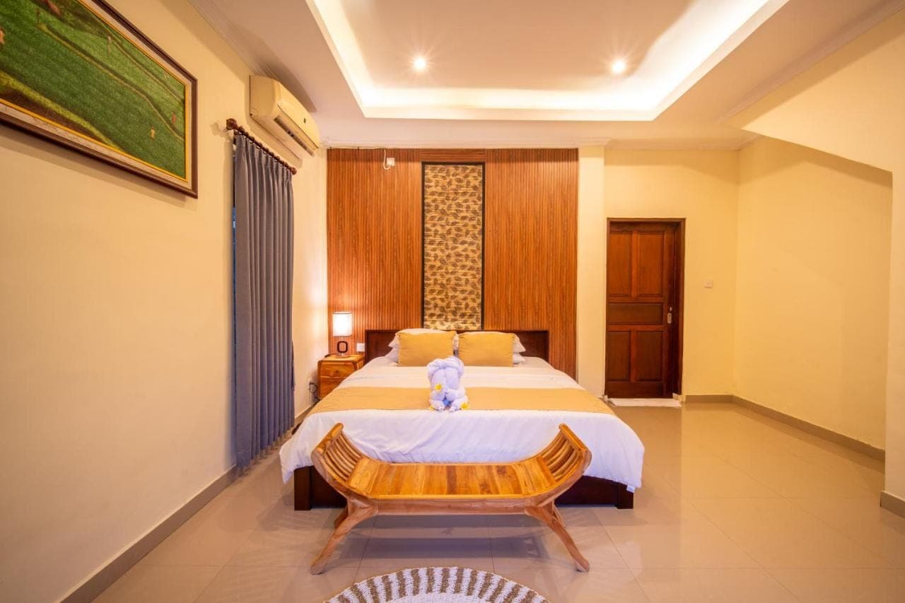 a bedroom with a bed with a teddy bear sitting on it at Alit Bungalow Ubud in Ubud