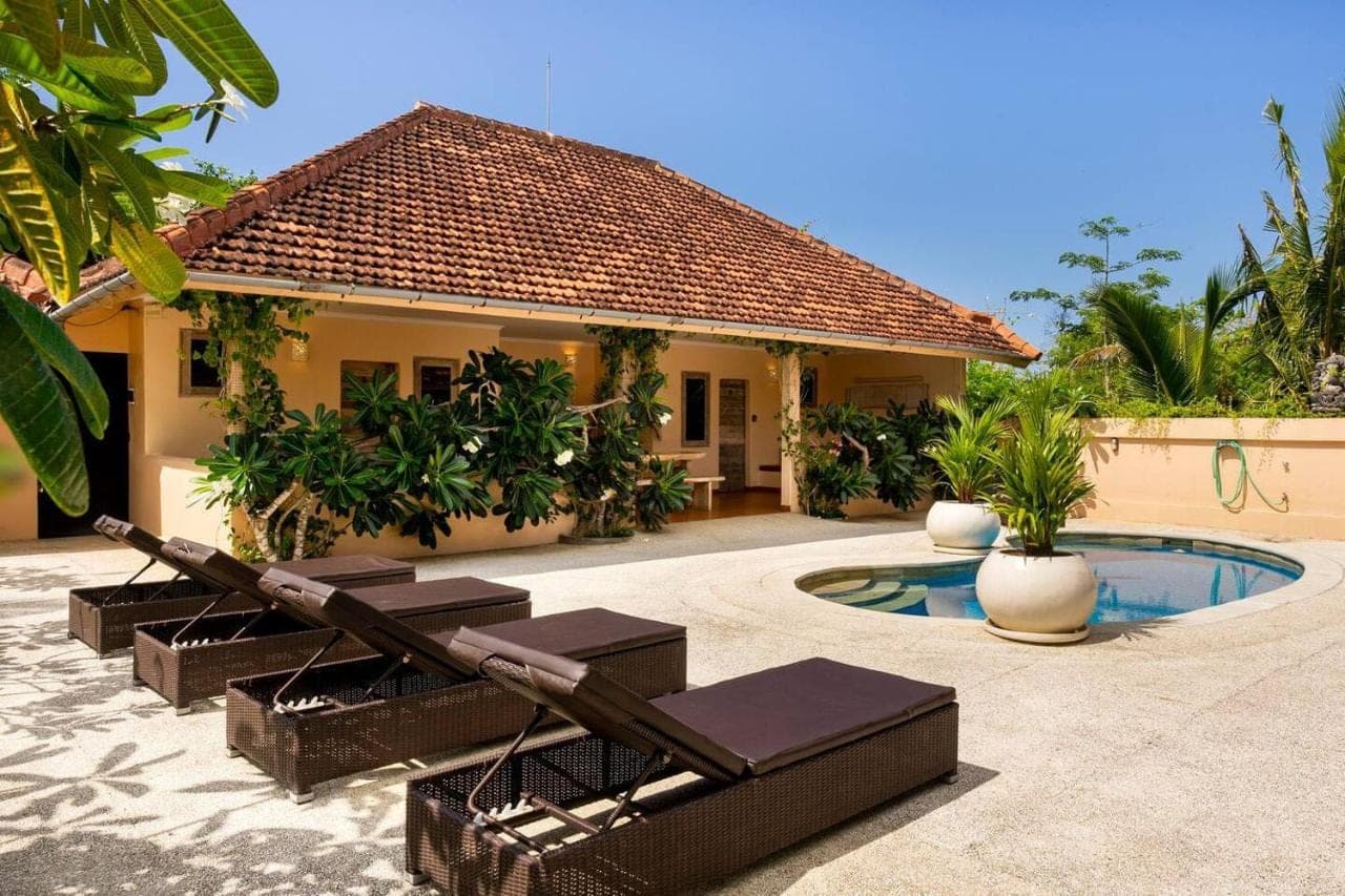 a house with a pool and chairs in front of it at Indahwatu in Uluwatu