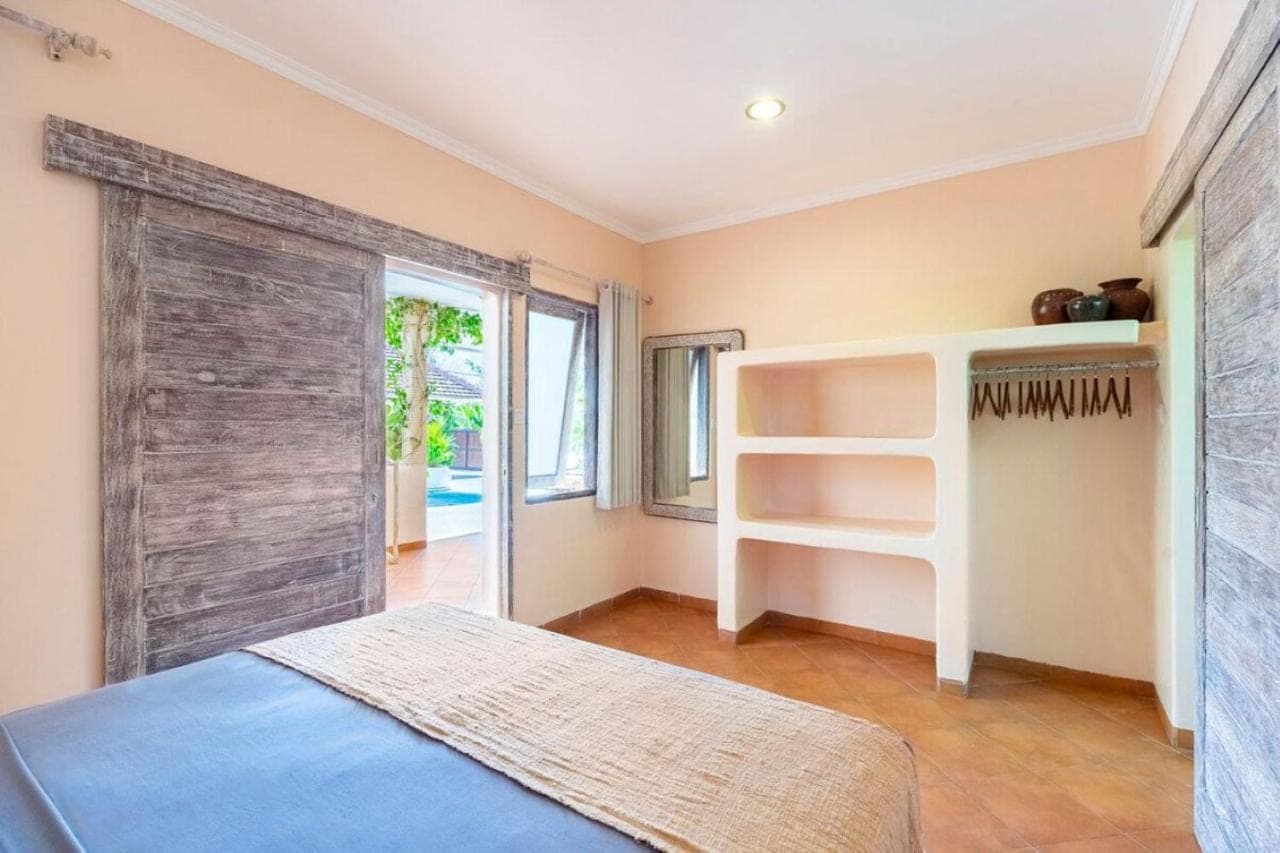 a bedroom with a bed and a sliding barn door at Indahwatu in Uluwatu