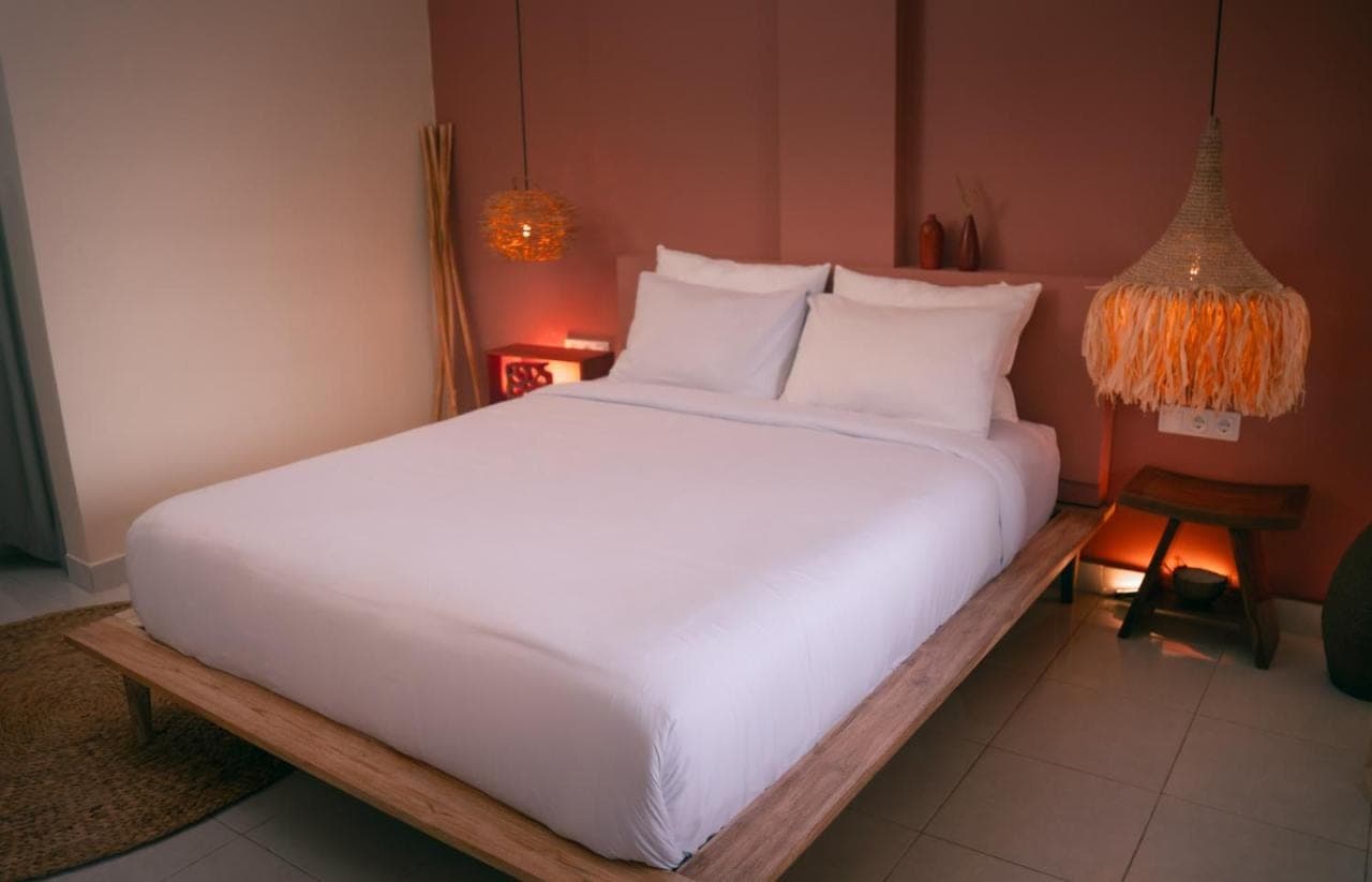 a bed with white sheets and pillows in a room at Pondok Sentana Uluwatu in Uluwatu