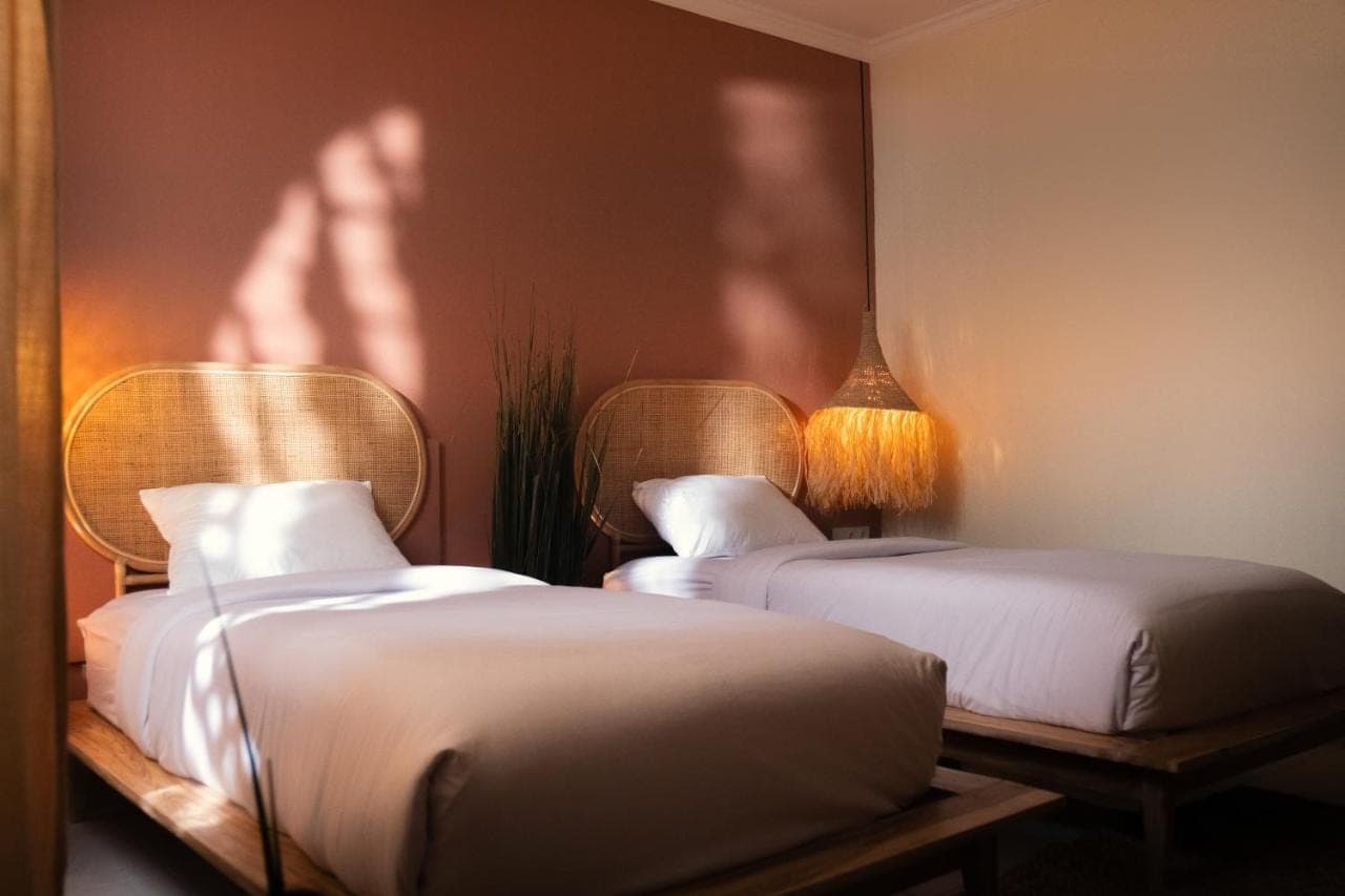 two beds in a room with a persons shadow on the wall at Pondok Sentana Uluwatu in Uluwatu