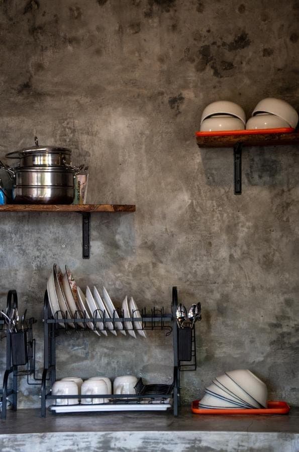 a kitchen with shelves filled with plates and pans at Pondok Sentana Uluwatu in Uluwatu