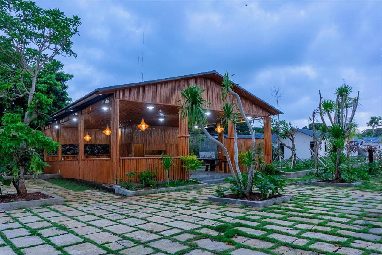 a wooden building with palm trees in front of it at Kotoa Villa 68 in Nusa Dua