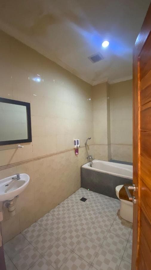 a bathroom with a sink and a tub and a toilet at Surya Inn in Kuta