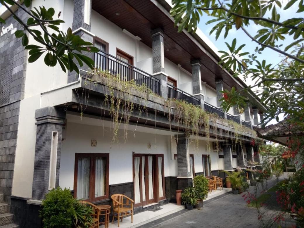 a building with a balcony and tables and chairs at Surya Inn in Kuta