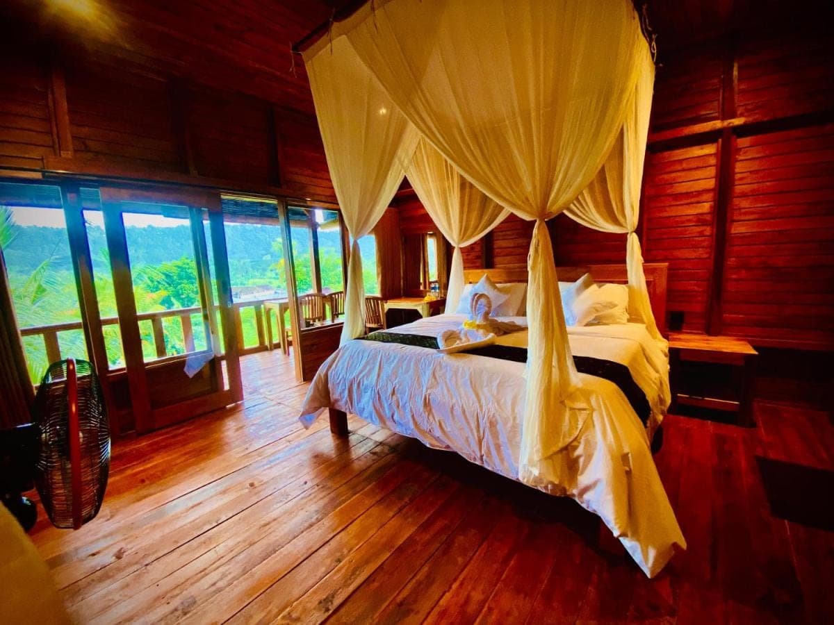 a bedroom with a bed in a room with windows at Manuk Dewata Villa in Sidemen