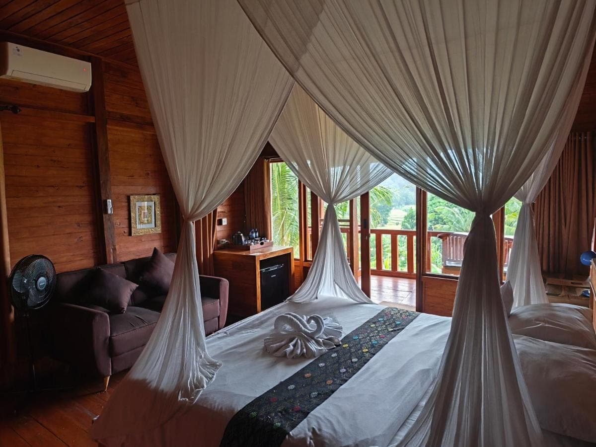 a bedroom with a bed with curtains and a couch at Manuk Dewata Villa in Sidemen