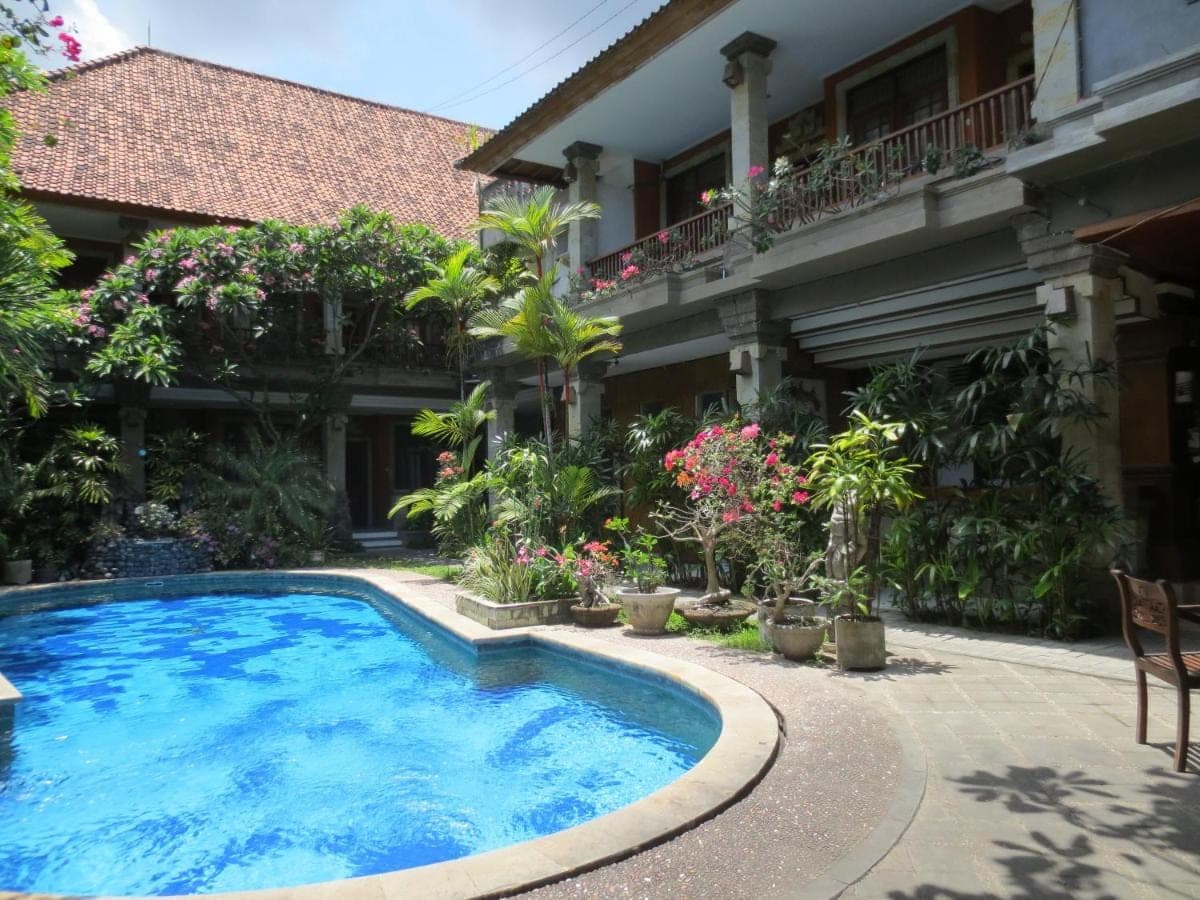 a swimming pool in front of a building at Swastika Guesthouse Sanur in Sanur