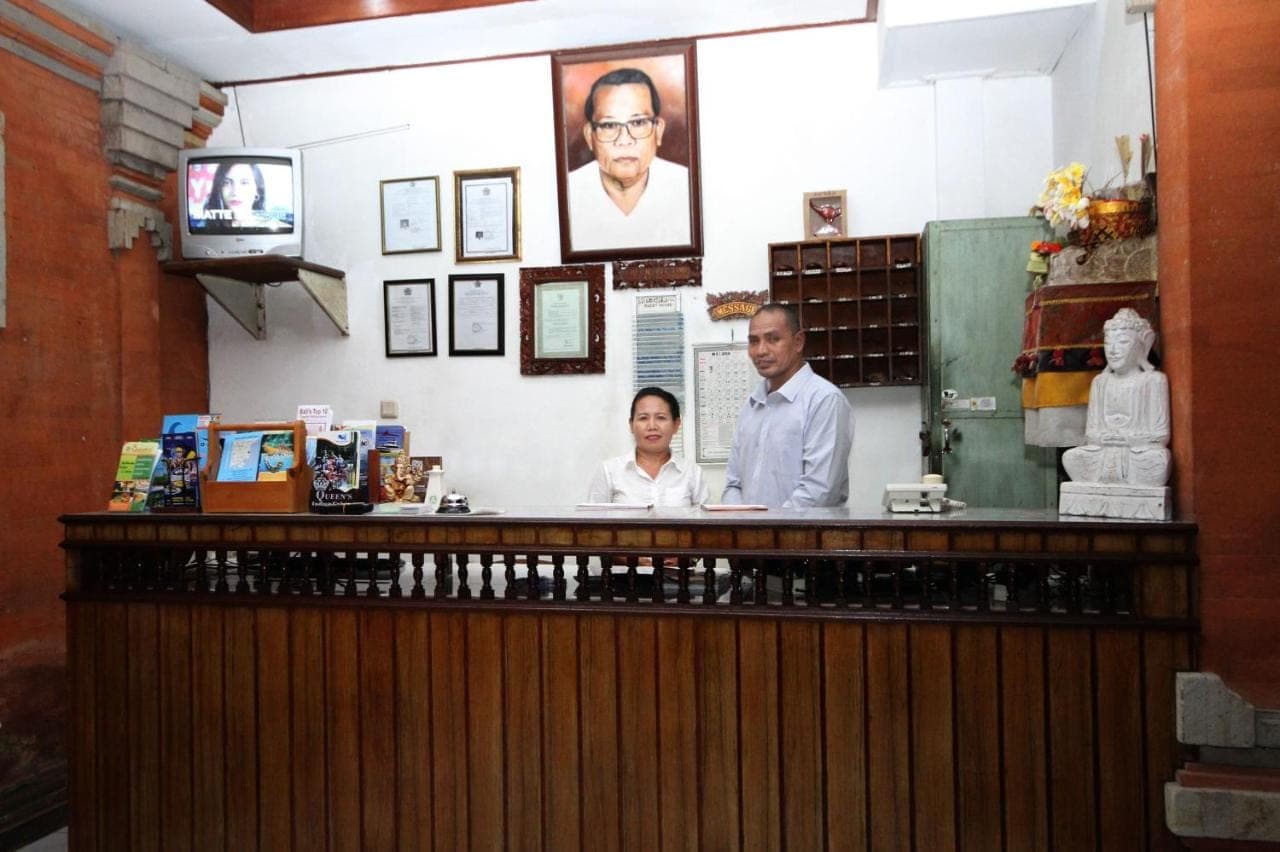 a couple of people standing at a counter in a restaurant at Swastika Guesthouse Sanur in Sanur