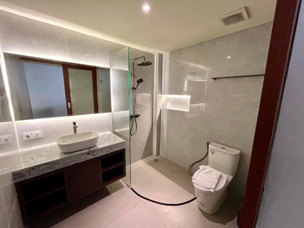 a bathroom with a toilet and a sink and a shower at Taman Agung Hotel in Sanur