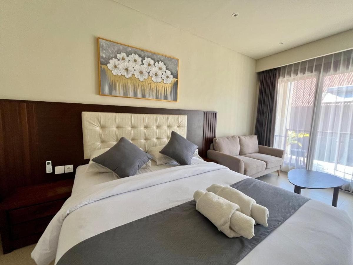 a bedroom with a large bed and a couch at Taman Agung Hotel in Sanur