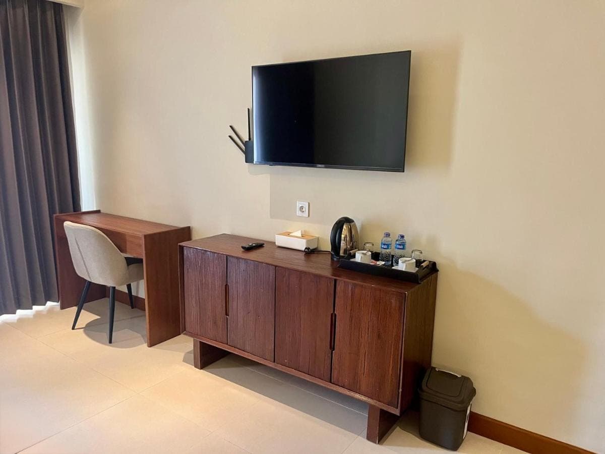 a hotel room with a desk and a television on the wall at Taman Agung Hotel in Sanur